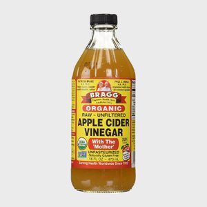 A clear bottle contains raw, unfiltered apple cider vinegar labeled 