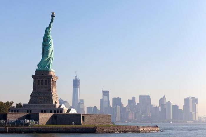 The Statue of Liberty free of tourists and New York City Downtown on sunny early morning