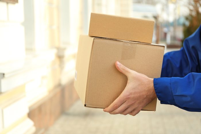 Courier with parcel in doorway, closeup (it's not real QR code)