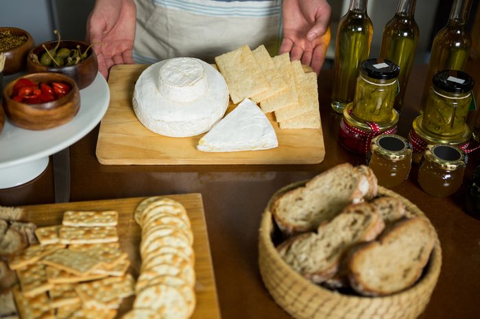 Staff standing near various cheeses at counter in grocery shop