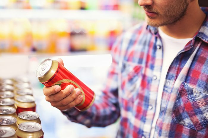 Man holding beer can in a liquor store, choosing beer