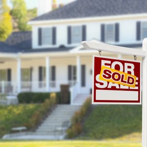 Sold Home For Sale Real Estate Sign in Front of Beautiful New House.