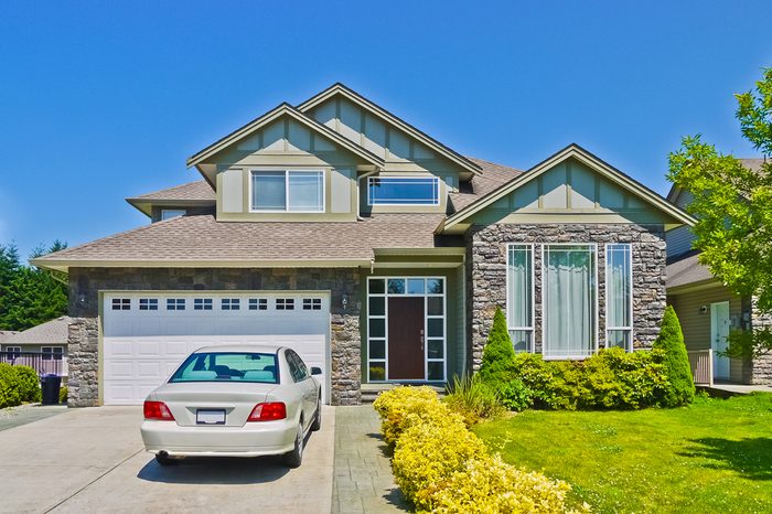 Luxury family house with luxury car parked on concrete driveway. Residential house on sunny day with blue sky background