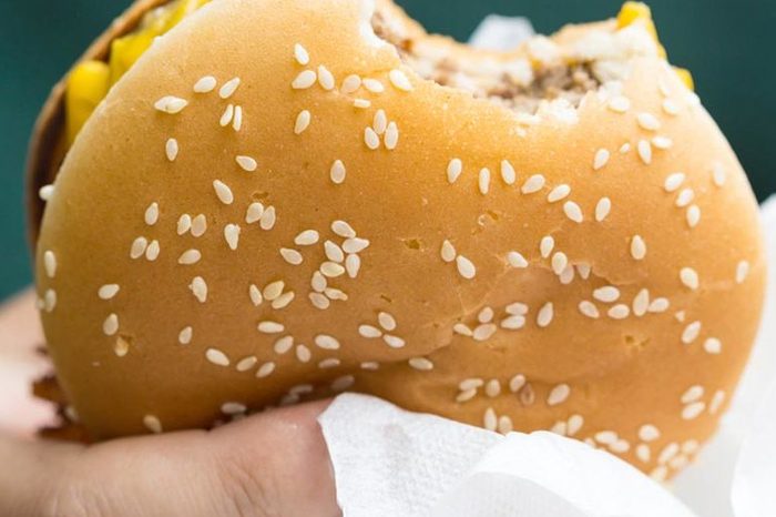 A fast food cheeseburger with a bite taken out of it / one bite taken out of it / Bitten hamburger.