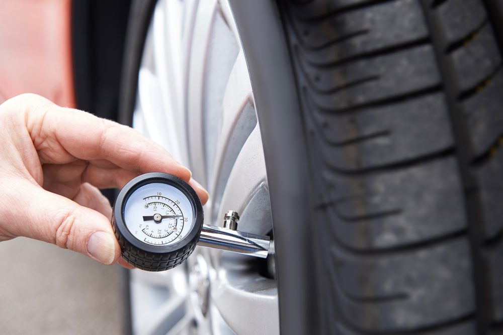 Man Checking Car Tire Pressure With Gauge
