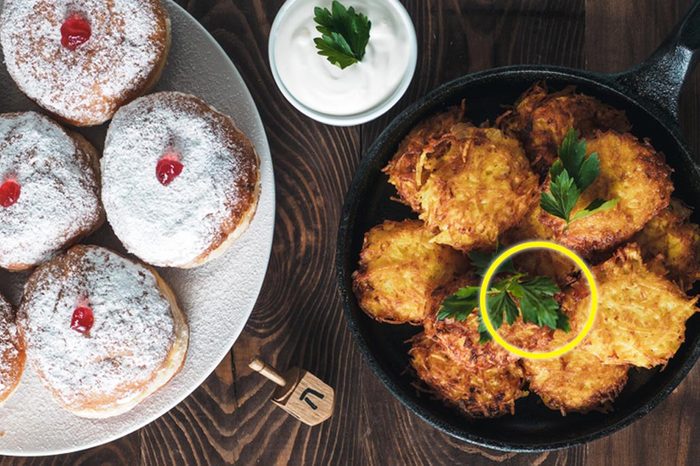 Jewish holiday Hanukkah concept and background. Hanukkah food doughnuts and potatoes pancakes latkes, oil and traditional spinnig dreidl on wooden table. Top view or flat lay. Copy space for text.