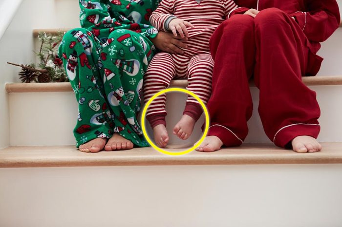 Three Children In Pajamas Sitting On Stairs At Christmas