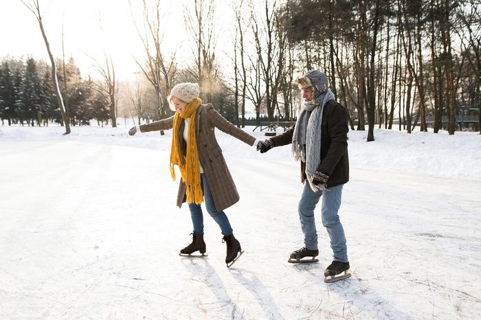 Senior couple in sunny winter nature ice skating.