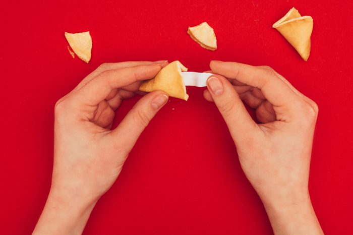 cropped shot of woman opening chinese fortune cookie, Chinese New Year concept