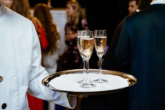 The waiter brings glasses of champagne