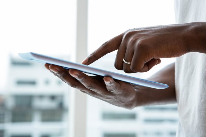 Close-up of man using digital tablet near window at home