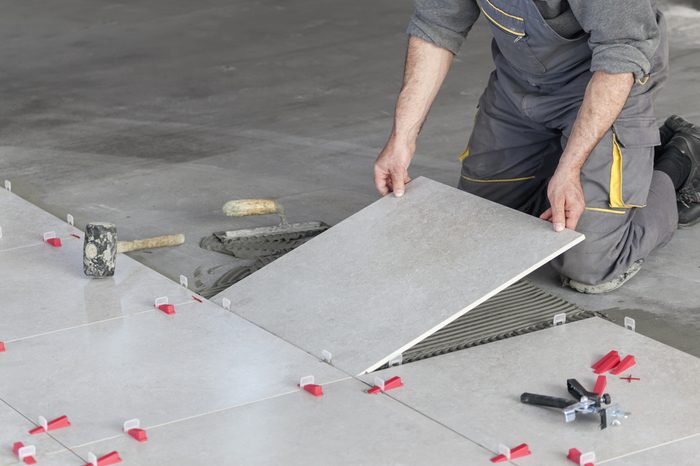 Ceramic Tiles. Tiler placing ceramic wall tile in position over adhesive with lash tile leveling system