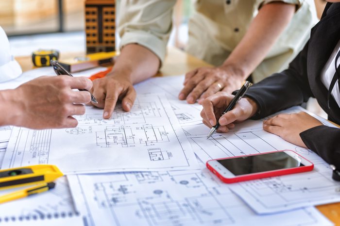 Image of team engineer checks construction blueprints on new project with engineering tools at desk in office.