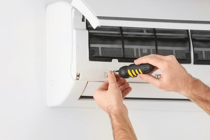 Male technician fixing air conditioner indoors