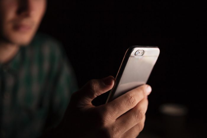 Closeup of man hand sitting and using smartphone in the evening