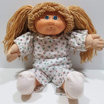 Doll sits wearing floral-patterned pajamas, surrounded by a plain background.