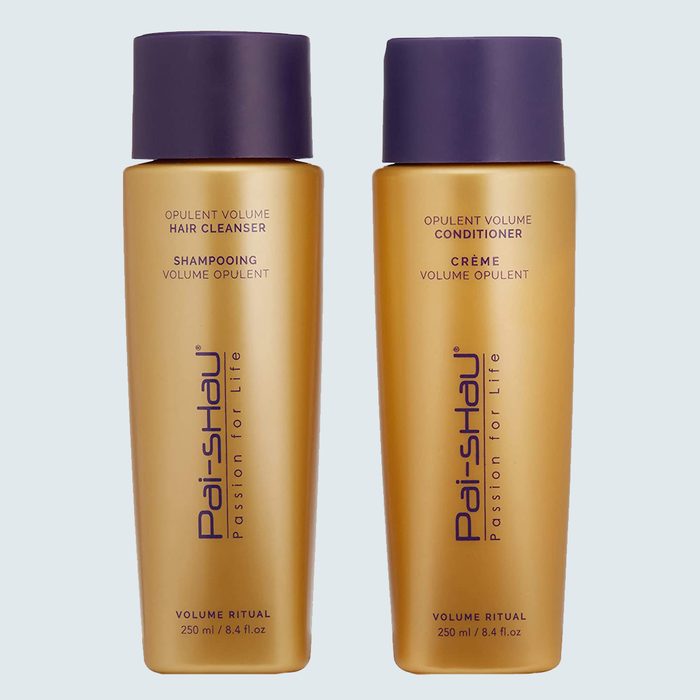 Two gold bottles stand side by side; one is shampoo, and one is conditioner, both labeled 