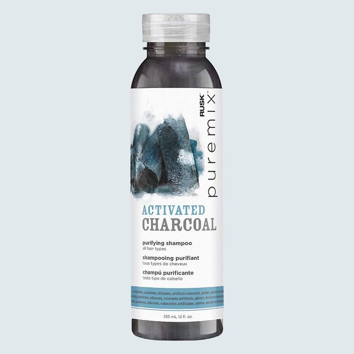 A bottle displays activated charcoal shampoo label, featuring blue-black abstract art, against a light background. Text includes 