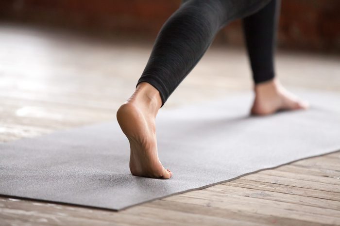 Young sporty woman practicing yoga, doing Warrior one exercise, Virabhadrasana 1 pose, working out, wearing black sportswear, indoor, yoga studio close up. Healthy lifestyle concept
