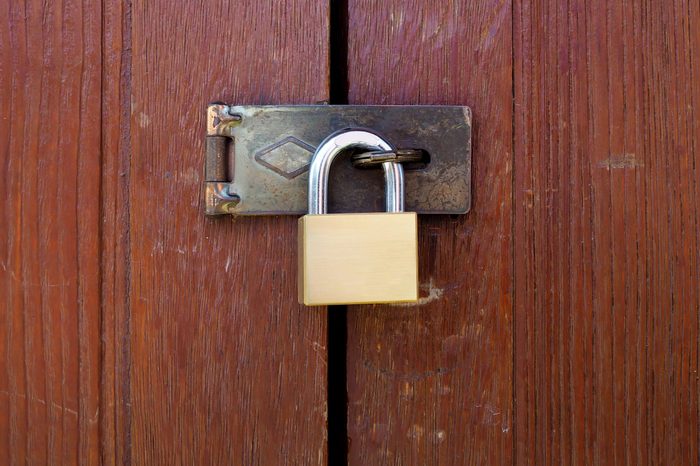 Locked padlock with chain at wooden door background, vintage, Closeup