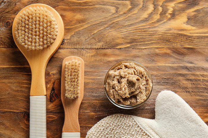Brushes and body scrub on wooden background