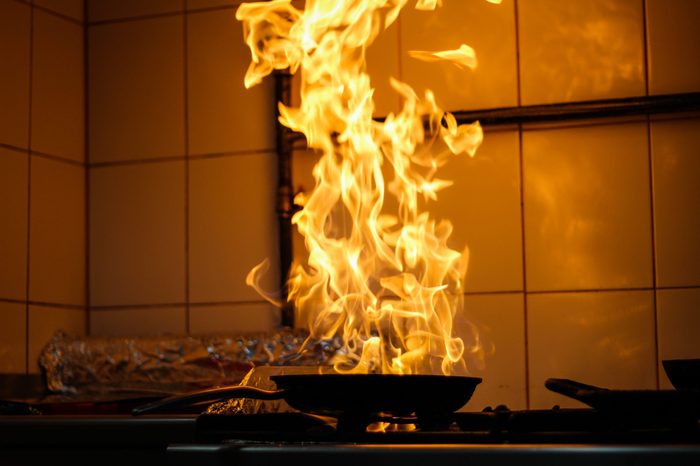 The chef cooking and makes a fire in a pan. Cooking with fire. Crown food.Flame on kitchen