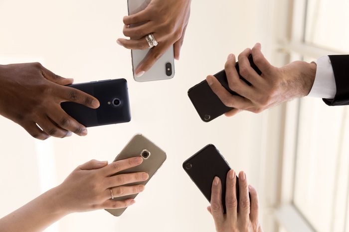 Male and female diverse hands holding cell phones, multiracial business people using smartphones applications software, users and devices concept, mobile communication, close up below bottom view
