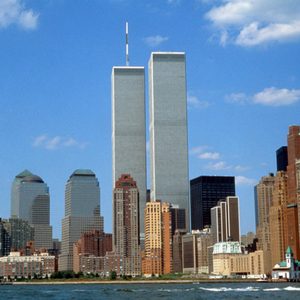 Twin skyscrapers stand tall, surrounded by a bustling cityscape with diverse buildings under a clear blue sky.
