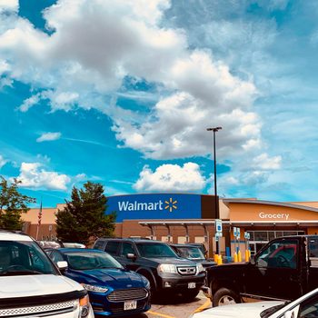 Cars parked outside Walmart under cloudy sky, with visible signage reading "Walmart" and "Grocery."