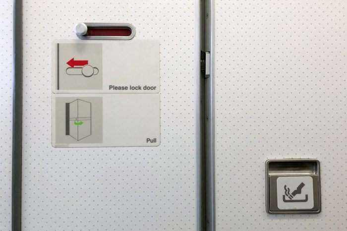 Airplane toilet. How to lock the door. Slide to lock (red color). No smoking. Copy space.