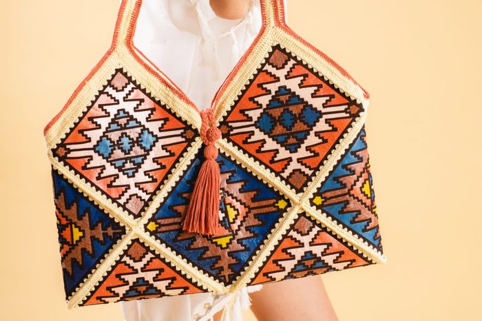 Fashionable Woman Wearing White Dress With Handmade Crochet Knitting Bag, Made From Many Colors Of Recycled Plastic Bags