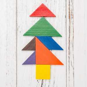 Colored geometric shapes form a tree on a white wooden background.