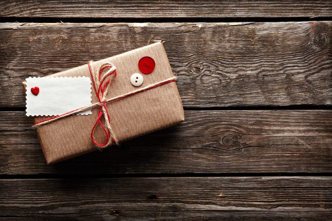 Vintage gift box (package) with blank gift tag on old wooden background.