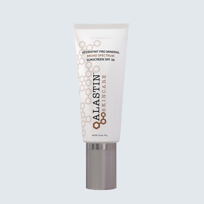 A tube of Alastin Hydratint Pro Mineral sunscreen stands upright against a light blue background.