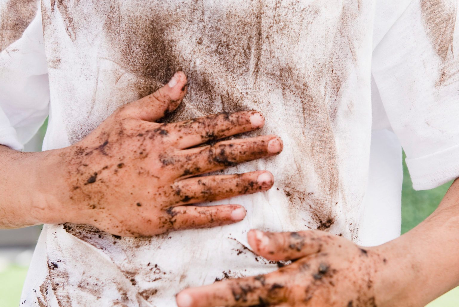 Mixed race boy wiping messy hands on shirt