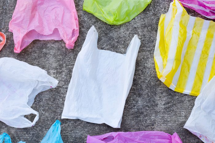 Plastic bags rest on a concrete surface, displaying various colors including white, pink, yellow, and blue.