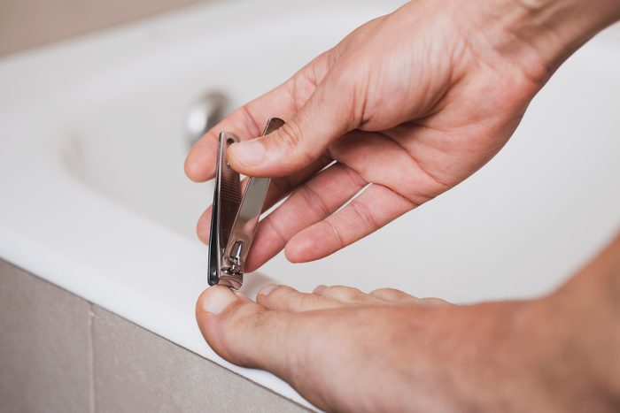 young man cutting his toenails