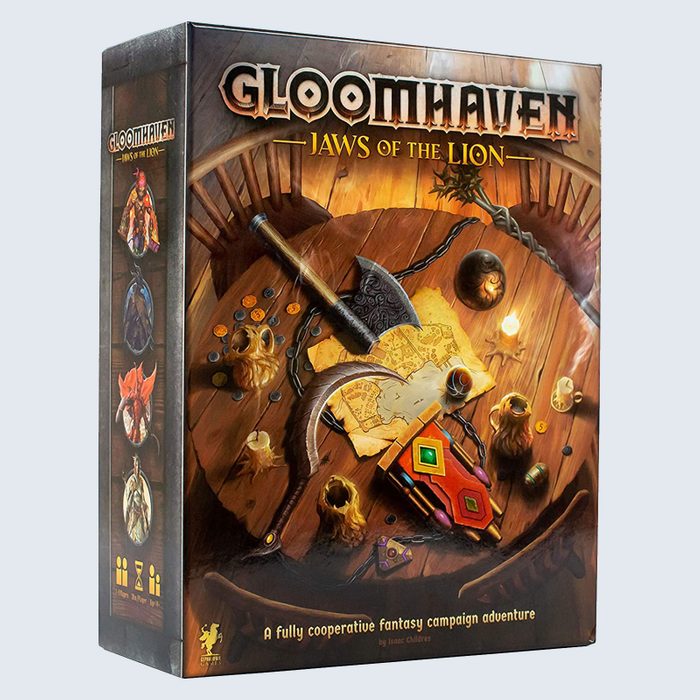 Box displays fantasy items atop a wooden table, featuring weapons and a map. Text reads: 