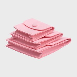 Pink folded cloth organizers stacked, each with a button closure, set against a plain white background.