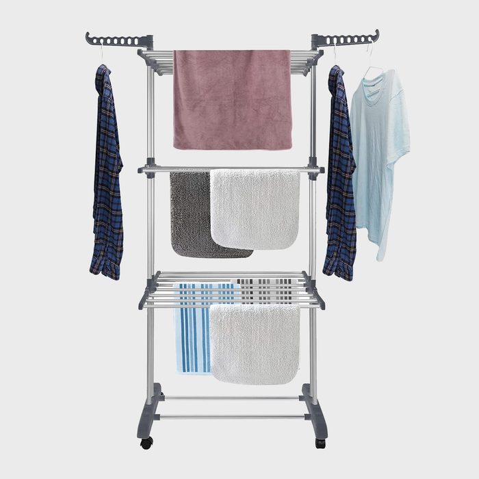 Clothes drying rack holds various garments and towels, set against a plain background, showcasing multiple hanging and shelved items.