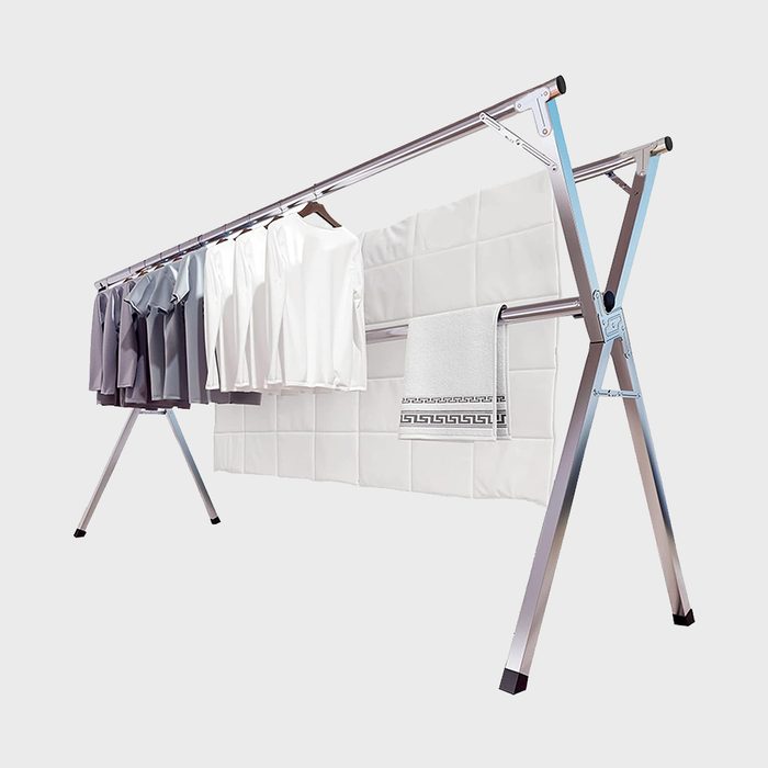Clothes rack holds shirts and towels, standing in front of a white tiled background.