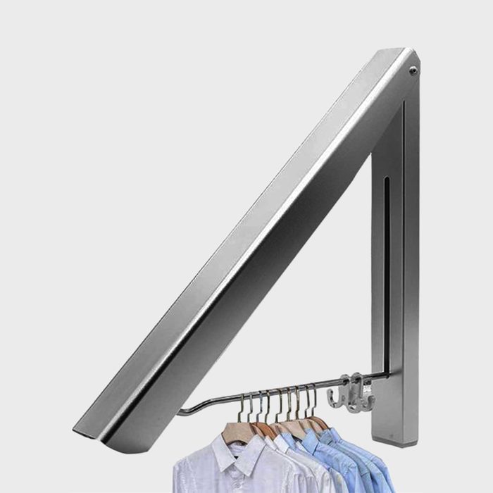 Clothes hang on a metal wall-mounted hanger, angled upward, against a neutral background.