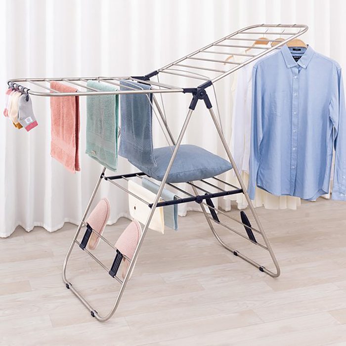 Drying rack holds towels and clothes, surrounded by a curtain backdrop.