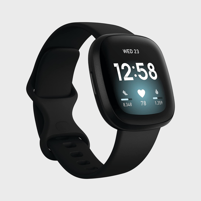 Smartwatch displays time, date, heart rate, steps, and calories; sleek black design, digital screen in a minimalistic setting.