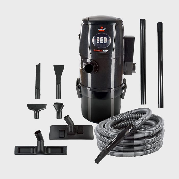 Wet/dry vacuum sits assembled with multiple attachments laid around, set against a plain backdrop; labeled 