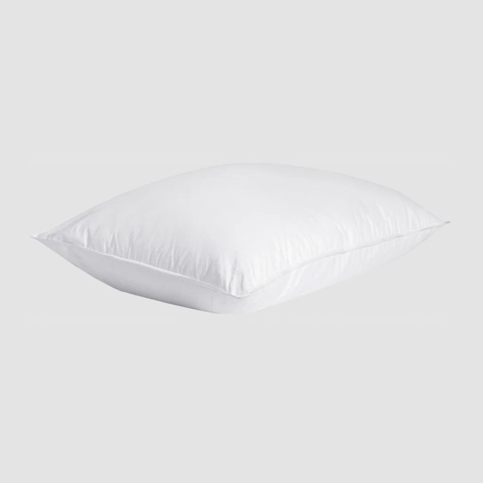A white pillow rests against a plain light-gray background, showcasing its clean and smooth texture.