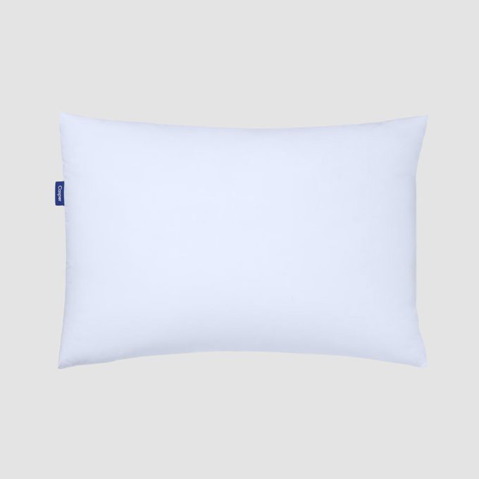A rectangular white pillow lies flat, with a small blue tag labeled 