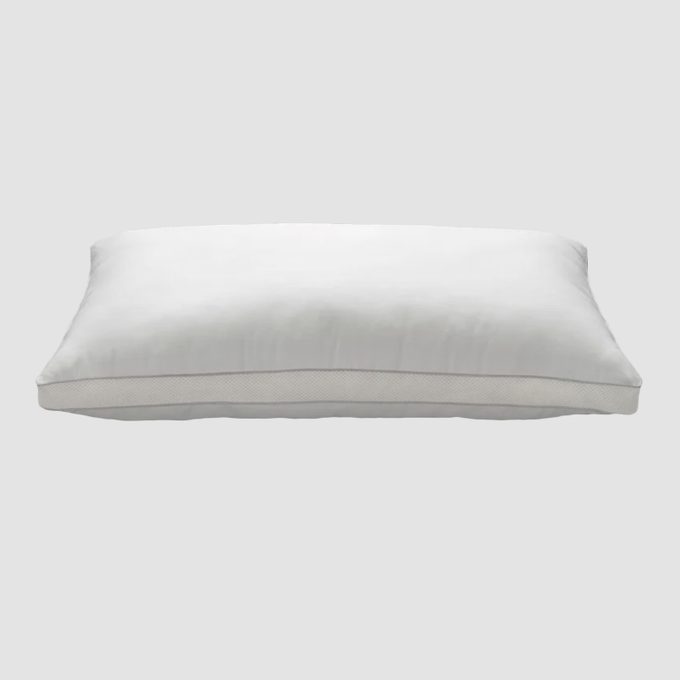 White pillow lies flat against a plain gray background, showcasing its rectangular shape and smooth texture.