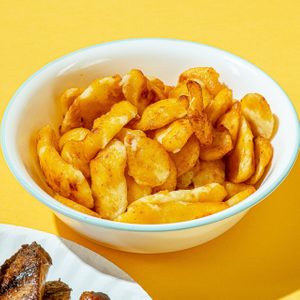 Golden gnocchi rests in a white bowl, set on a vibrant yellow surface.