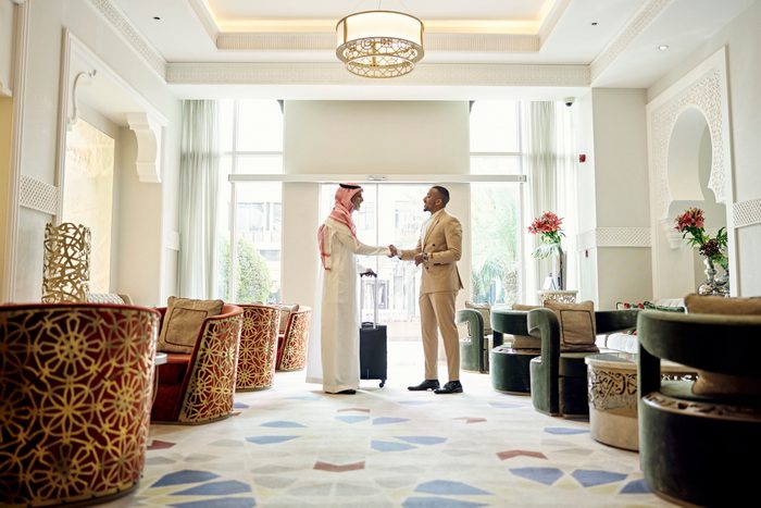 Saudi businessman shaking hands with client in hotel lobby